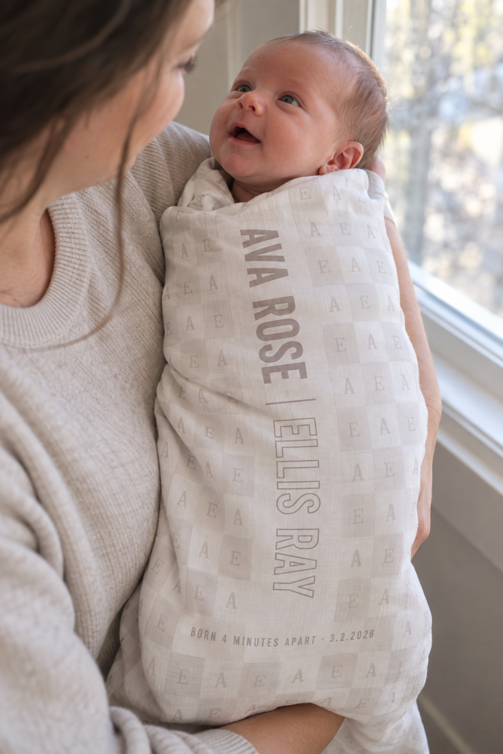 A custom swaddle blanket printed with a first name and stacked birth details in clean type