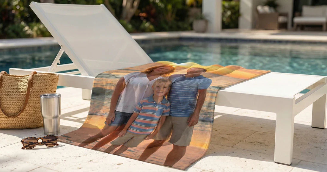 Premium personalized beach towel draped poolside with a vivid photo-led design, styled with a beach bag and summer accessories for a polished Custom Envy blog hero.