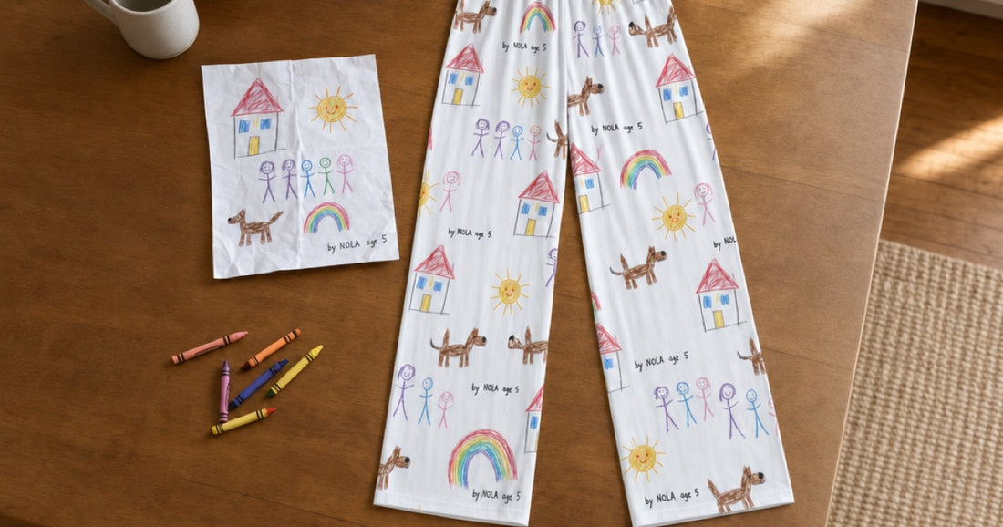 Custom white pajama pants printed with a child's drawings beside the original artwork and crayons.