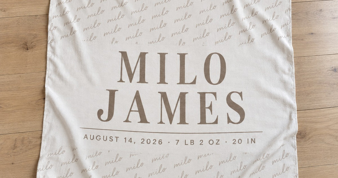 Custom baby swaddle blanket laid flat with the name Milo James and birth details printed across one side.