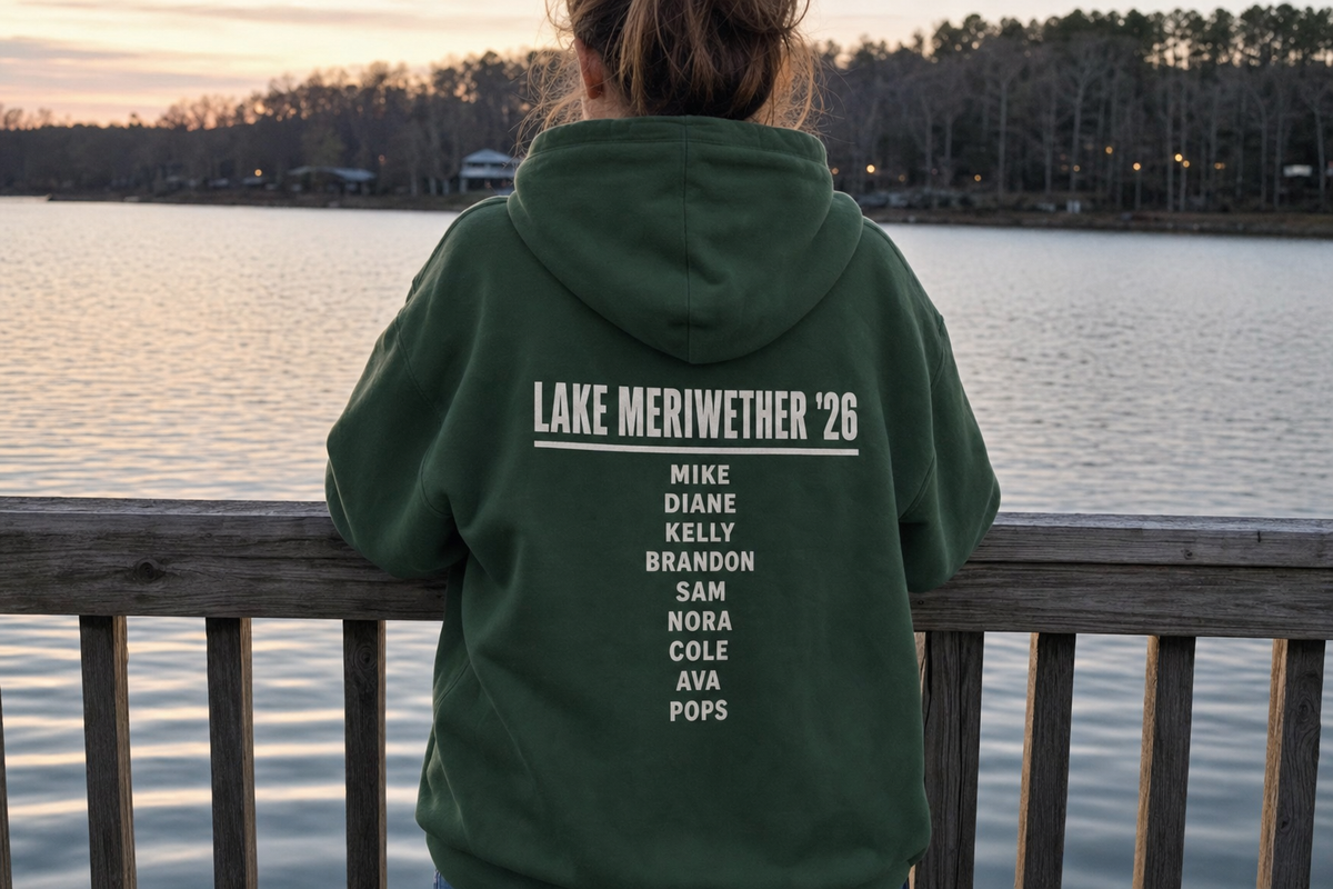 The back of a forest green custom hoodie printed with a lake trip headline and a roster of family names