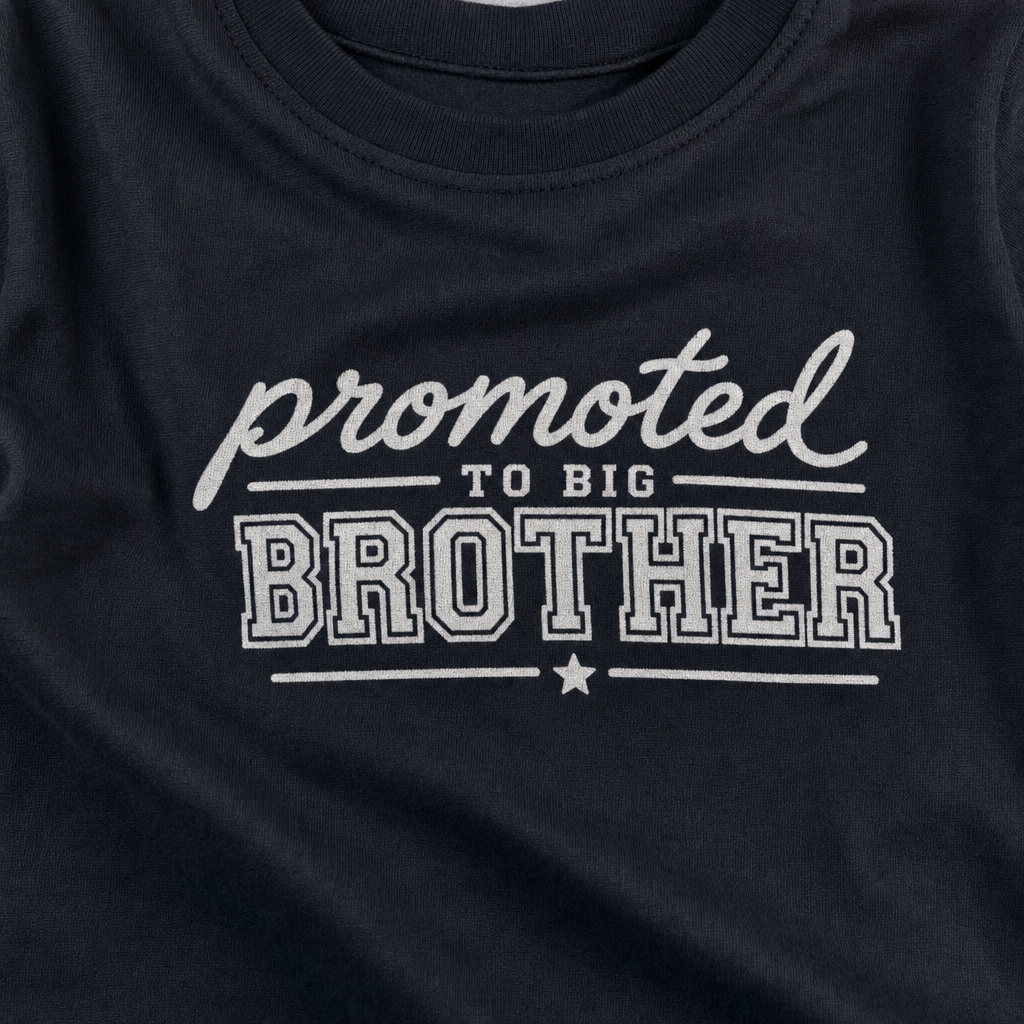 Close-up of a PROMOTED TO BIG BROTHER text print on the fine jersey knit of a custom infant tee