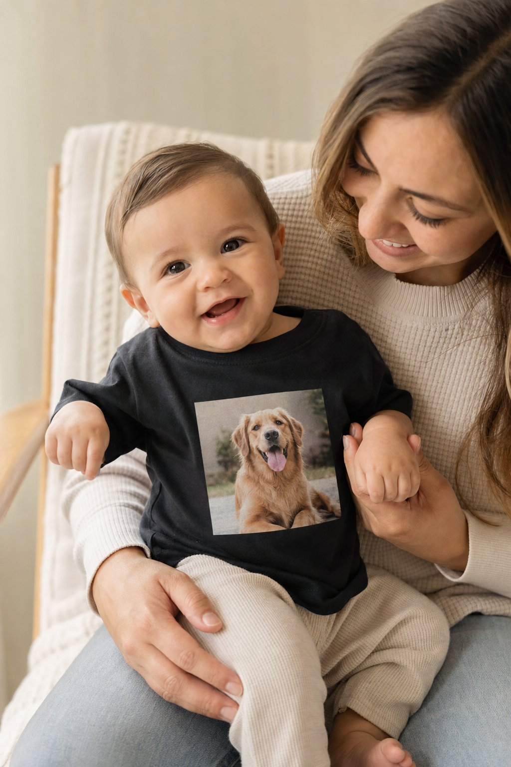 Baby sitting on a parent's lap wearing a black infant tee printed with a golden retriever photo