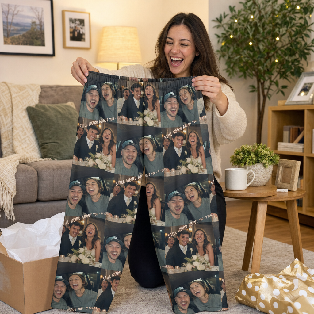 A gift recipient laughing while holding up custom pajama pants printed with a couple's photos