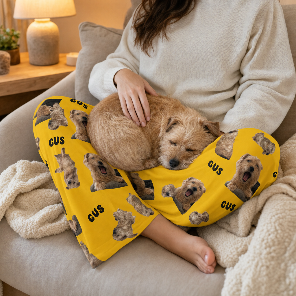 A woman wearing custom pajama pants printed with her terrier's photos while the same dog naps on her lap