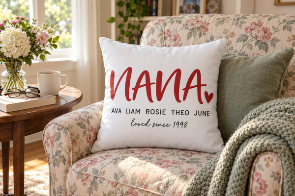 White throw pillow reading Nana with five grandkids' names on a floral reading chair