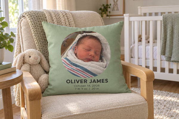 Sage throw pillow with a newborn photo, the name Oliver James and birth stats on a nursery glider
