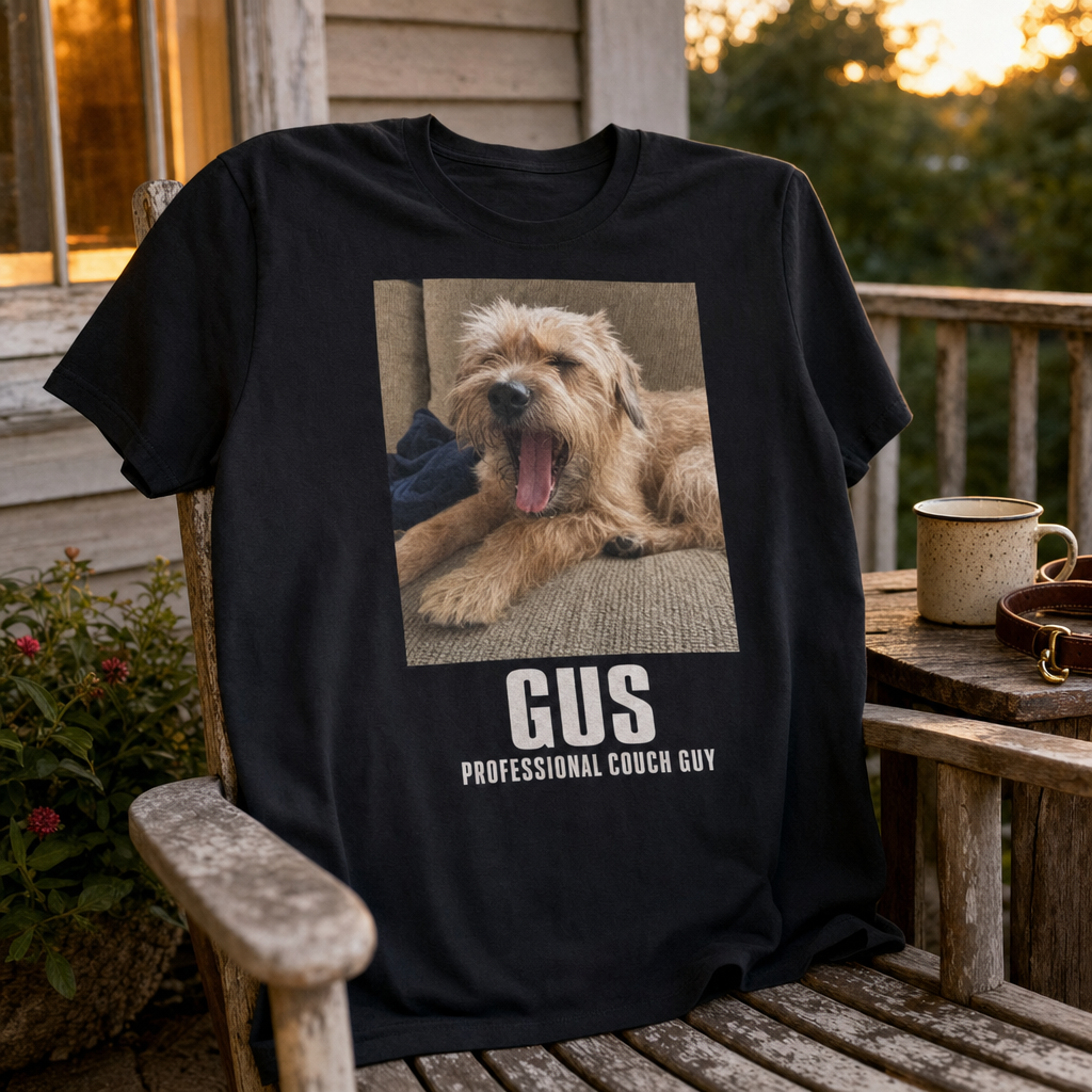 Black custom t-shirt printed with a candid terrier photo and the name Gus, draped over a porch chair at golden hour