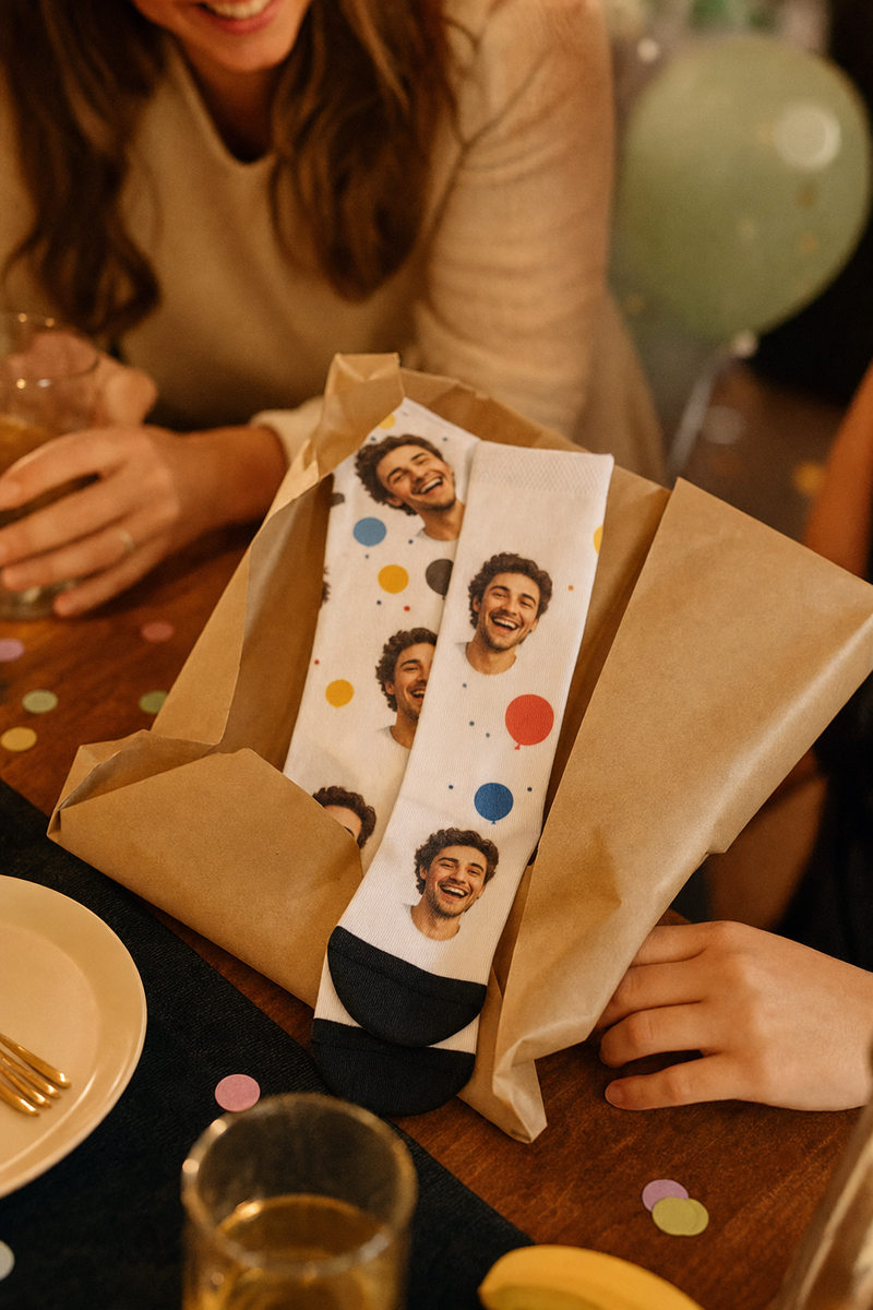 Custom face socks half unwrapped from kraft paper at a birthday table